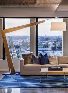 a living room filled with lots of furniture and large windows overlooking the cityscape