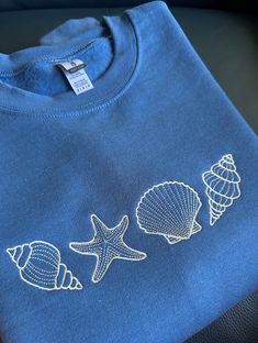 Perfect for a seaside trip, or throwing it on after a beach day! Cute embroidered seashell sweatshirt a great addition to your closet.  Custom Available:  - Size can be made bigger if required, please reach out to us - different color sweatshirts available, Crewnecks & Hoodies - different thread colors available  If you would like to purchase multiple sweatshirts or a different color or a change in design, please contact me first!  All requests are welcome! Sizing : These sweatshirts are in ADUL Cute Embroidered Hoodies, Lake Sweatshirt Ideas, Blue Cotton Beach Sweatshirt, Blue Cotton Sweatshirt For Beach, Cricket Sweatshirt Ideas, Embroidery Patterns Sweatshirt, Seashell Clothes, Embroidery Designs Shirt, Cute Embroidered Sweatshirt