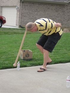 a man bending over with a baseball bat and water bottles on the ground next to him