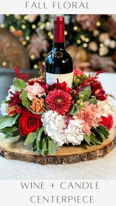 a bottle of wine sitting on top of a wooden slice with flowers and greenery