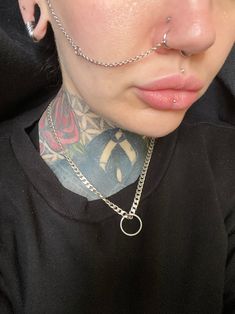 a woman with piercings on her nose wearing a black shirt and silver chain necklace