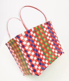 This charming 1970s style accessory features a vibrant color combo of red, green, blue, and white that screams retro chic. The durable plastic material ensures this bag will be your go-to for all your sunny day outings. With convenient plastic handles, you can easily carry all your essentials in style.Available while supplies last. Fun Red Bags For Daily Use, Fun Multicolor Plastic Bags, Retro Red Bags For Summer, Retro Red Summer Bag, Retro Red Summer Bags, Fun Red Bags For Everyday Use, Fun Red Tote Bag, Retro Red Square Bag, Red Retro Square Bag