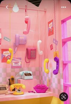 there are many telephones on the wall in this pink and yellow room with checkered walls