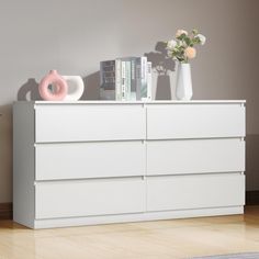 a white dresser with books and vases on top