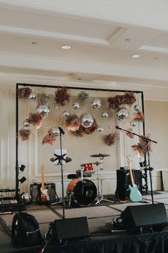 a stage set up for a concert with musical instruments and decorations on the wall behind it