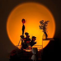 a basket with flowers in it sitting next to a light that is shining on the wall