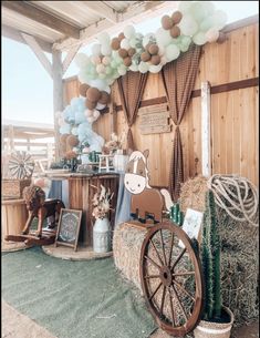 an outdoor area with hay bales, balloons and other items on the ground in front of a wooden wall