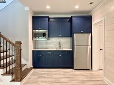 an empty kitchen with blue cabinets and white counter tops is seen in this image from the hallway