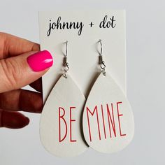 Get your Valentine's Day look on point with these Be Mine Faux Leather Teardrop Earrings! Made with white faux leather, these earrings feature the words "Be" and "Mine" written in red. Perfect for adding a touch of love and style to any outfit. Measures 2 1/2 inches long x 1 1/2 inches wideUltra lightweight weight .10 ounces Buy Earrings, Hand Wrap, Be Mine, Look On, Cute Earrings, Teardrop Earrings, The Words, Of Love, Valentine's Day