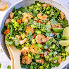 a bowl filled with shrimp and vegetables next to a glass of beer on the side