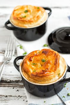 two pot pies sitting next to each other on top of a white wooden table