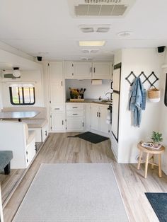 the inside of a travel trailer with wood flooring and white cabinets, blue accents