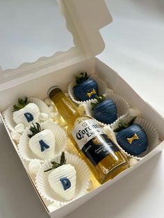 a bottle of beer and some chocolate covered strawberries in a white box with blue letters