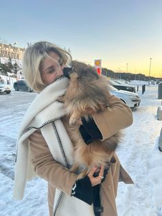 a woman is holding a dog in the snow