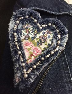 a denim jacket with an embroidered heart on the back and pearls hanging from it's pockets