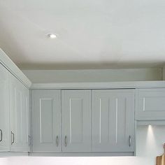 a kitchen with white cabinets and wooden cutting board