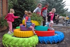 children playing in an outdoor play area made out of old tires and tire rims