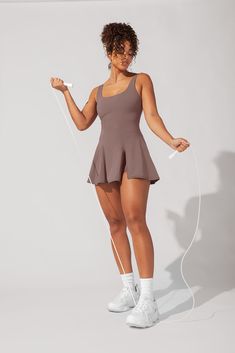 a woman in a short skirt and white tennis shoes is holding a pair of headphones