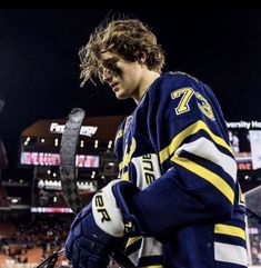 a hockey player is holding a snake in his hand and looking down at the ground