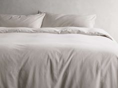 an unmade bed with white sheets and pillows