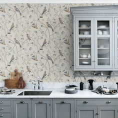 a kitchen with grey cabinets and wallpaper