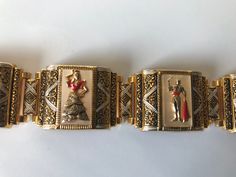 "Gorgeous gold gilt and mother of pearl in-laid Spanish toledo damascene five link bracelet featuring a lady dressed in a flamenco dress and a bull fighter in alternate panels. The bracelet has a push in slide closure and also comes with a safety chain. According to Wikipeda \"Damascening is the art of inlaying different metals into one another--typically, gold or silver into a darkly oxidized steel background--to produce intricate patterns similar to niello\". Approximate measurements: Bracelet Festive Ornate Bracelets, Vintage Bracelets For Festivals, Collectible Yellow Gold Bracelets, Vintage Yellow Gold Festive Jewelry, Enamel Bracelet Jewelry For Wedding, Festive Vintage Yellow Gold Jewelry, Formal Engraved Jewelry For Festivals, Collectible Gold Jewelry For Festivals, Traditional Enamel Jewelry Collectible