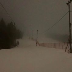 a person riding skis down a snow covered slope at a ski resort on a cloudy day