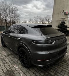 a grey porsche cayen parked in front of a building on a cobblestone street