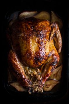 a roasted chicken in a roasting pan with potatoes