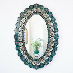 a round mirror hanging on the wall above a potted plant