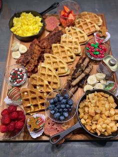 a wooden platter filled with waffles, fruit and other foods on top of it