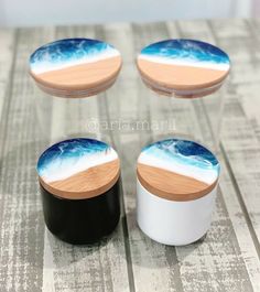 three small jars with wooden lids are sitting on a table