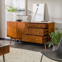 a living room with furniture and pictures on the wall, including a sideboard in between two chairs