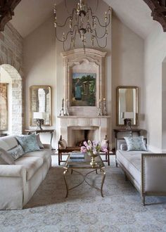 a living room filled with furniture and a chandelier hanging from the ceiling over a fire place