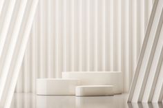 three white objects sitting on top of a table next to striped wallpaper and flooring