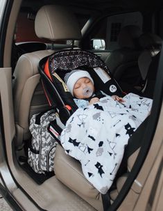 a baby sleeping in a car seat with a blanket on it's back and head