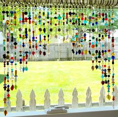 a window covered in lots of different colored beads and chains hanging from it's side