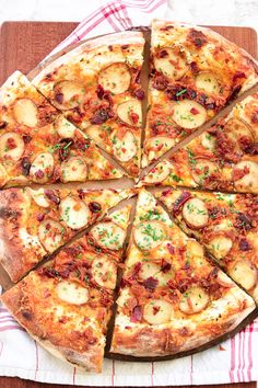 a pizza cut into eight slices on top of a wooden cutting board with a red and white checkered towel