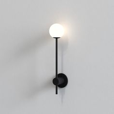 a black wall light with a white ball on it