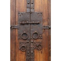 an old wooden door with metal latches and rivets on the front panel