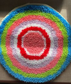 a multicolored circular rug on top of a white table with a red circle in the middle