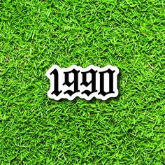 a sticker with the word dgn on it in black and white, laying on green grass