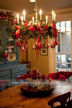 a chandelier with christmas decorations hanging from it's sides and candles in the middle