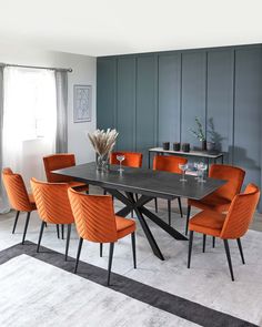 a dining room table with orange chairs around it