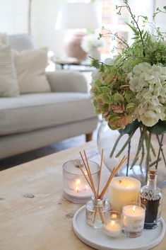 a table with candles and flowers in vases on top of it next to a couch