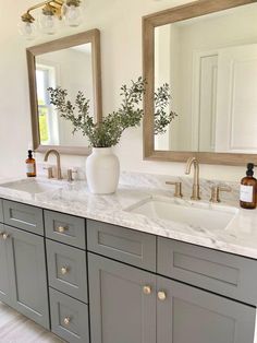 a bathroom with two sinks and mirrors in the corner, one has a vase on it