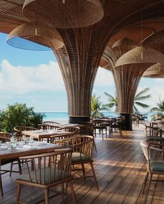 an outdoor dining area with tables and chairs overlooking the ocean on a wooden floor that is lined with wicker umbrellas