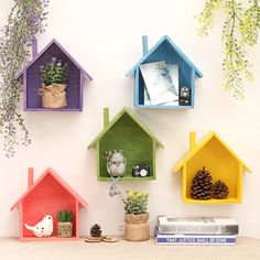 colorful bird houses are hanging on the wall next to books and potted planters