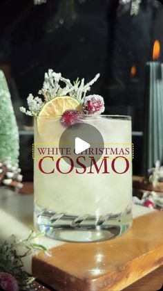 a white christmas cosmo cocktail sitting on top of a wooden table