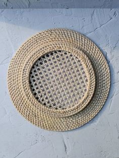 a white wall with a round rattan basket hanging on it's side